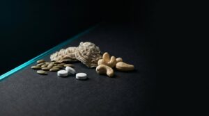 Semillas de calabaza, anacardos, ostras y comprimidos de zinc sobre fondo negro con luz cian