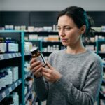 Mujer en una farmacia leyendo la etiqueta de un bote de suplemento